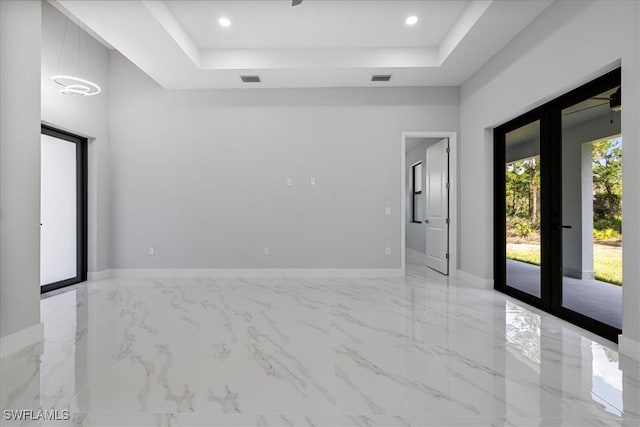 spare room featuring a tray ceiling and french doors