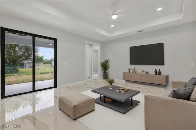 living room with a tray ceiling and ceiling fan