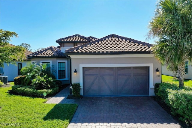 mediterranean / spanish-style home featuring a garage, a front lawn, and central air condition unit