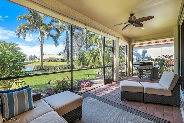 sunroom with ceiling fan and a water view