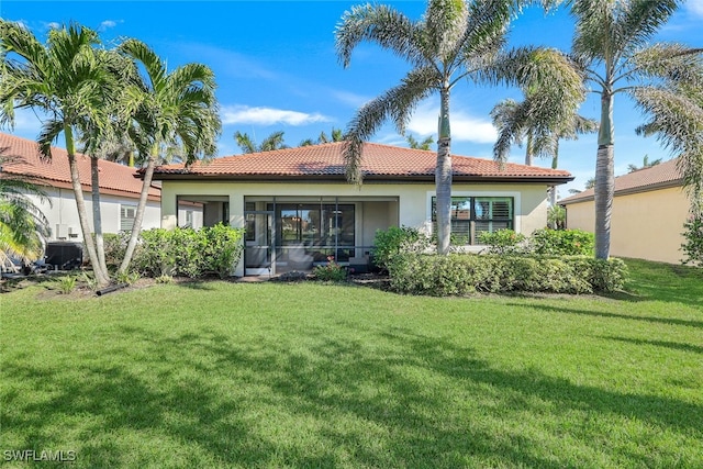 rear view of house featuring a lawn and a sunroom