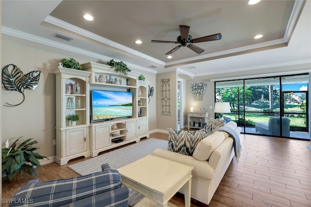 living room featuring light wood-type flooring, a tray ceiling, and ceiling fan