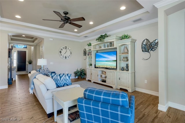 living room featuring a tray ceiling, ceiling fan, crown molding, and hardwood / wood-style flooring