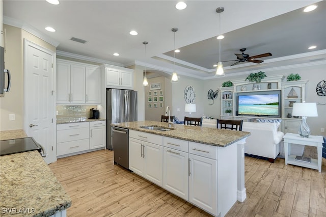 kitchen featuring appliances with stainless steel finishes, white cabinetry, a kitchen island with sink, and sink