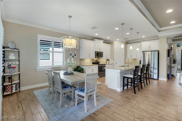 dining room featuring crown molding, sink, and light wood-type flooring