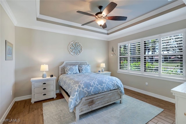 bedroom featuring ceiling fan, light hardwood / wood-style floors, a raised ceiling, and crown molding