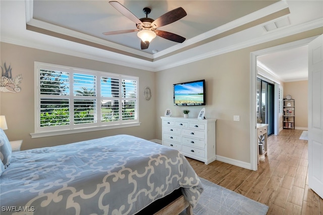 bedroom featuring a tray ceiling, ceiling fan, crown molding, and light wood-type flooring