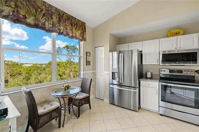 kitchen featuring lofted ceiling, plenty of natural light, stainless steel appliances, and white cabinetry