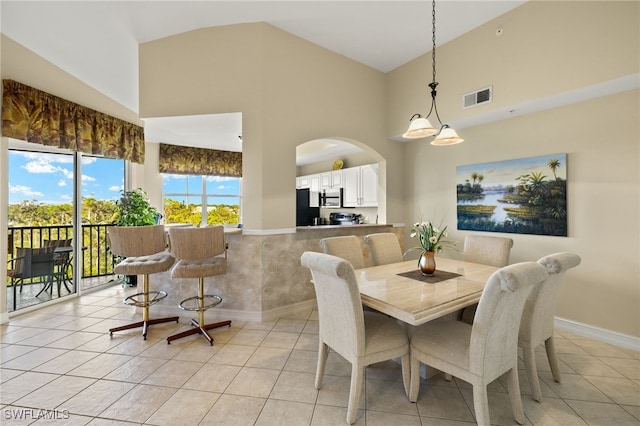 dining space with light tile patterned floors and high vaulted ceiling