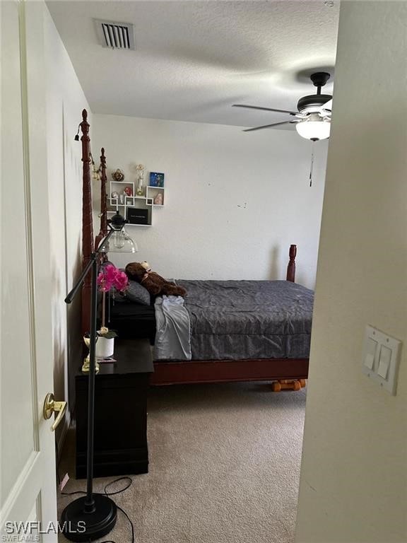 carpeted bedroom with ceiling fan and a textured ceiling