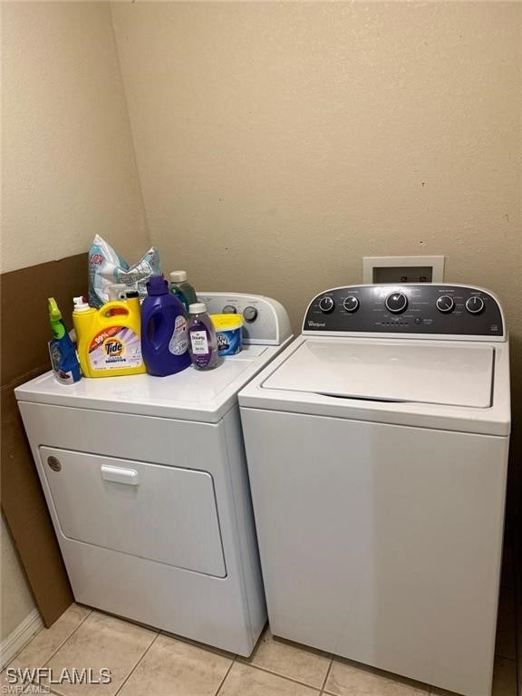 clothes washing area with separate washer and dryer and light tile patterned floors