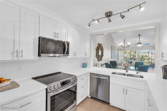 kitchen featuring sink, white cabinetry, stainless steel appliances, and vaulted ceiling