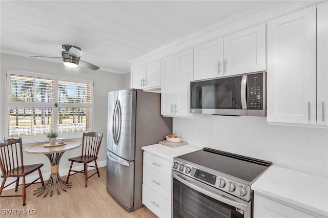 kitchen with crown molding, appliances with stainless steel finishes, white cabinets, and ceiling fan