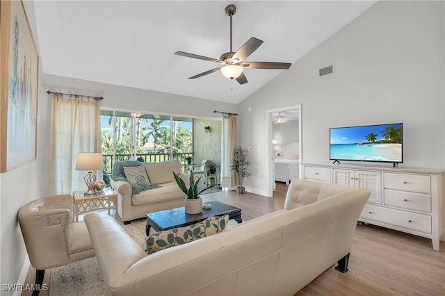 living room with high vaulted ceiling, ceiling fan, and light hardwood / wood-style flooring