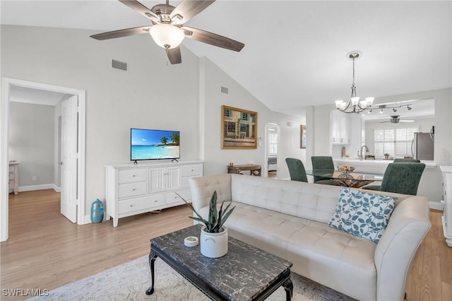 living room with ceiling fan with notable chandelier, lofted ceiling, sink, and light hardwood / wood-style flooring