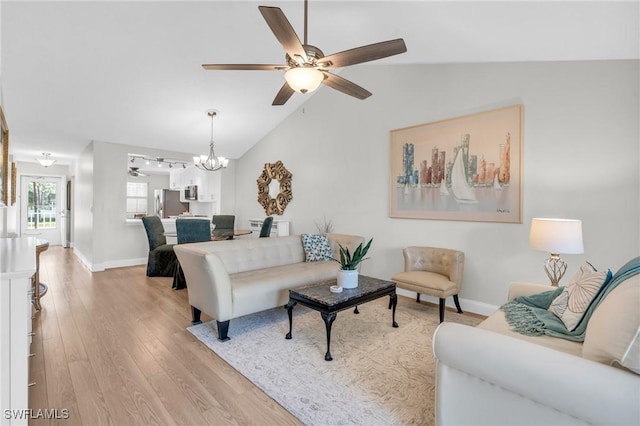 living room featuring vaulted ceiling, ceiling fan with notable chandelier, and light hardwood / wood-style flooring