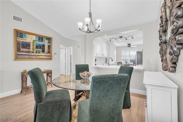 dining room featuring vaulted ceiling, ceiling fan with notable chandelier, and light hardwood / wood-style flooring