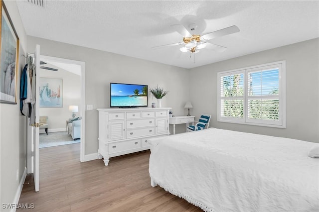 bedroom featuring ceiling fan, a textured ceiling, and light wood-type flooring