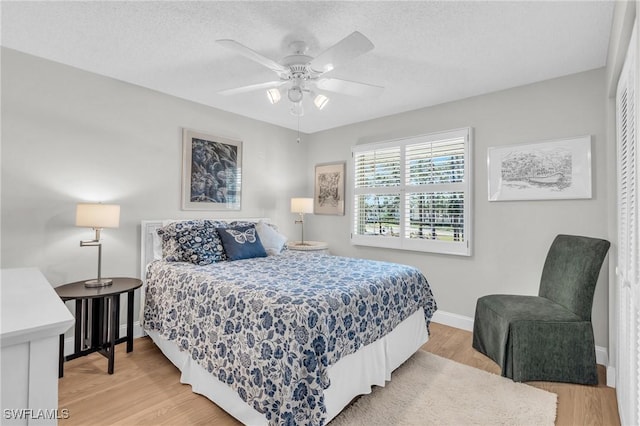 bedroom featuring a textured ceiling, light hardwood / wood-style floors, and ceiling fan