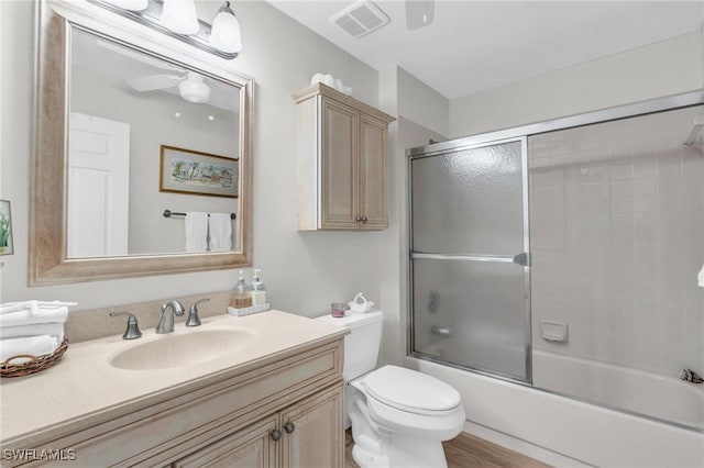 full bathroom featuring vanity, ceiling fan, enclosed tub / shower combo, and toilet