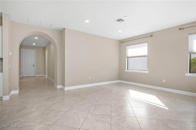 spare room with baseboards, visible vents, arched walkways, and recessed lighting