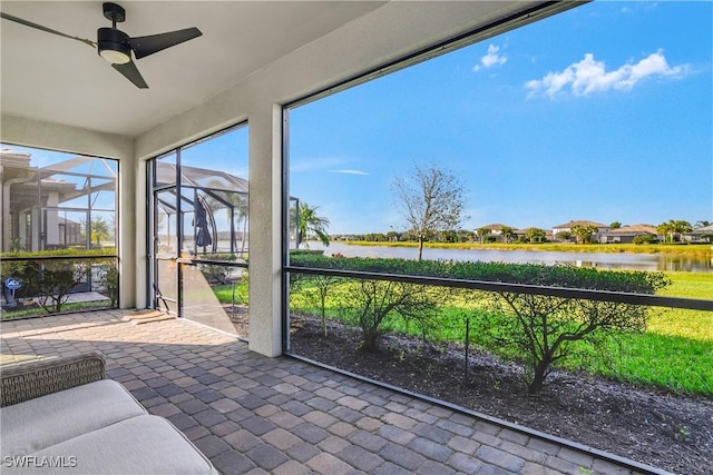 sunroom with ceiling fan and a water view