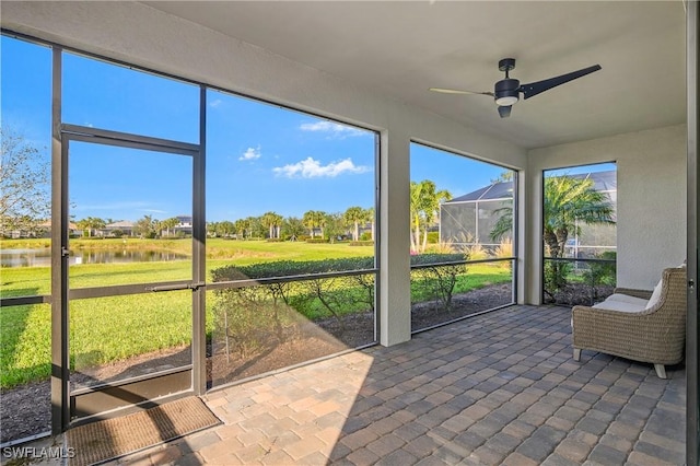 unfurnished sunroom featuring ceiling fan and a water view