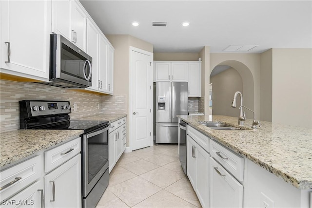 kitchen featuring stainless steel appliances, an island with sink, visible vents, and white cabinets