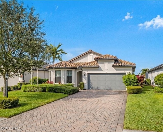 mediterranean / spanish home featuring a garage, a tiled roof, decorative driveway, and a front yard