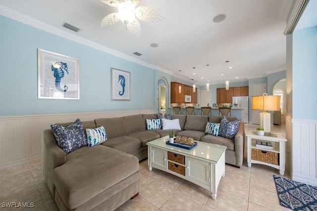 living room with light tile patterned floors, crown molding, and ceiling fan