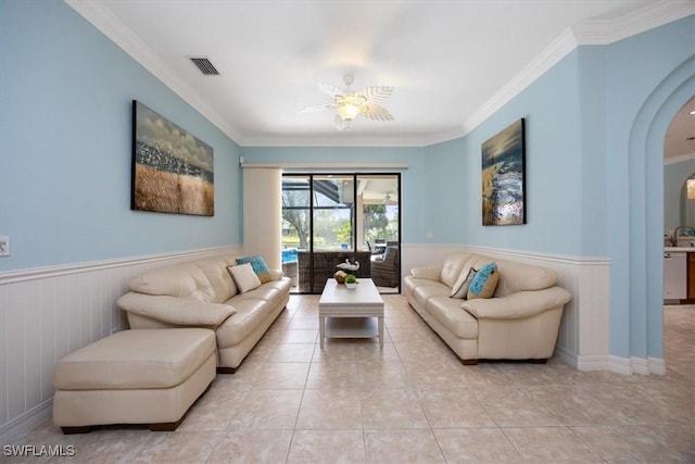 living room featuring tile patterned flooring, wainscoting, visible vents, and crown molding