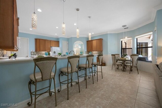 kitchen featuring hanging light fixtures, tasteful backsplash, light tile patterned floors, and crown molding