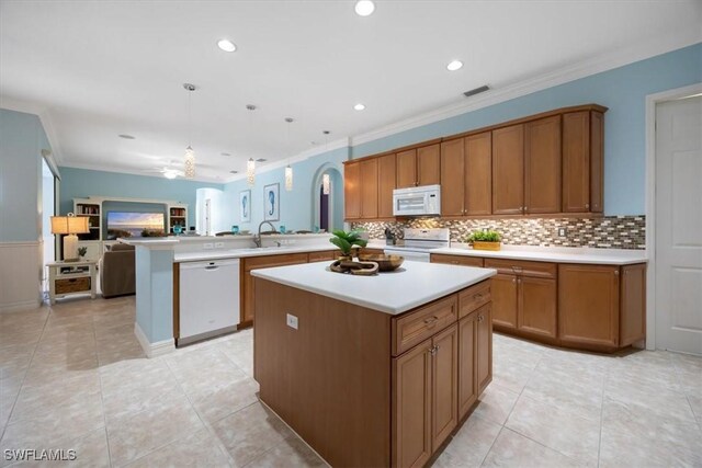 kitchen with pendant lighting, sink, white appliances, a kitchen island, and kitchen peninsula