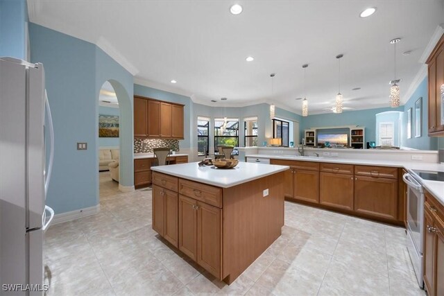 kitchen featuring a kitchen island, a healthy amount of sunlight, pendant lighting, and white appliances