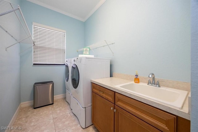 washroom featuring light tile patterned flooring, sink, cabinets, washing machine and clothes dryer, and crown molding