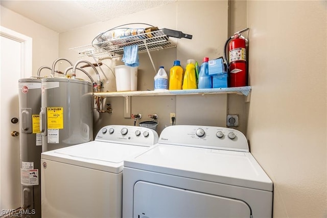 clothes washing area with washer and clothes dryer, electric water heater, and a textured ceiling