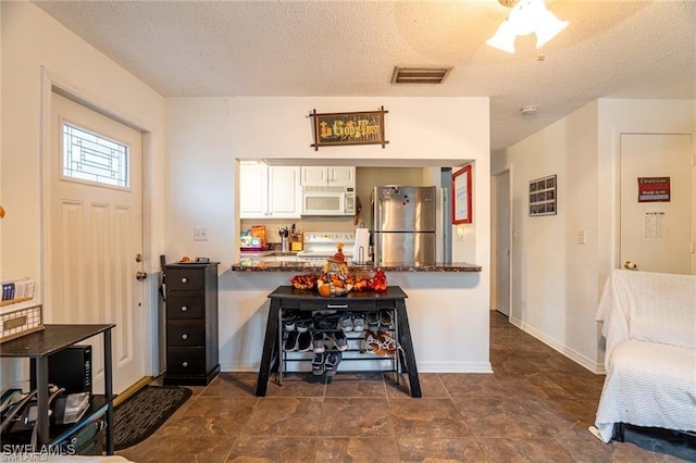 kitchen with range, white cabinets, stainless steel fridge, a textured ceiling, and kitchen peninsula