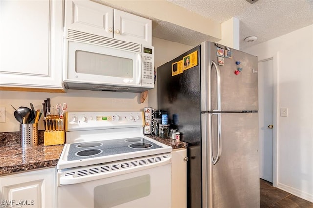 kitchen featuring white appliances, dark stone counters, white cabinets, dark tile patterned flooring, and a textured ceiling