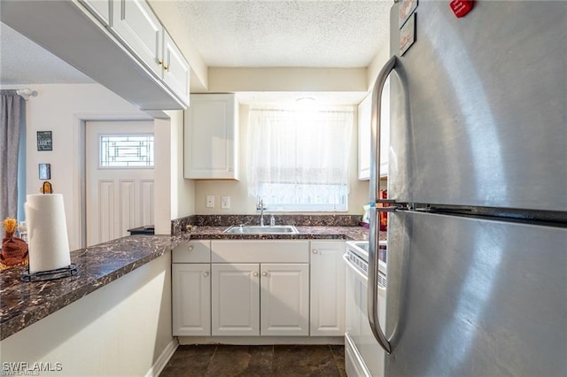 kitchen featuring white cabinets, sink, stainless steel fridge, a textured ceiling, and range