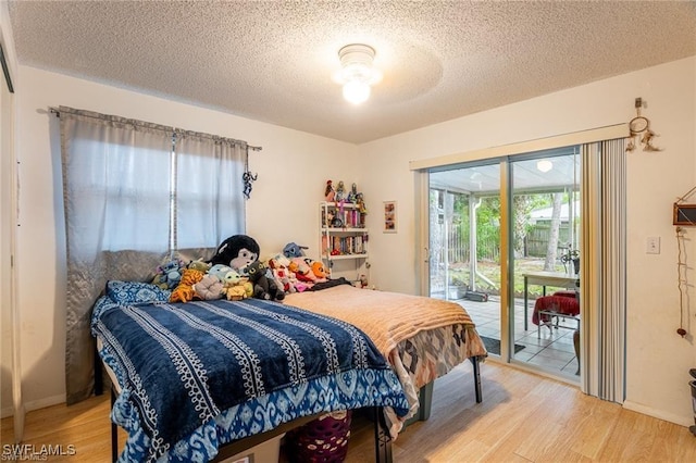 bedroom featuring ceiling fan, wood-type flooring, a textured ceiling, and access to outside