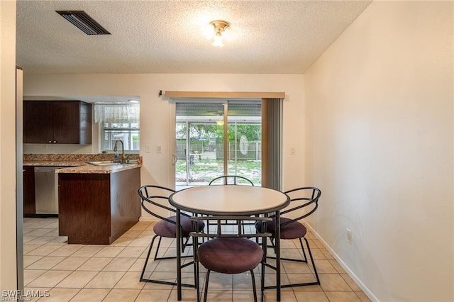 dining room featuring a textured ceiling, light tile patterned floors, and sink