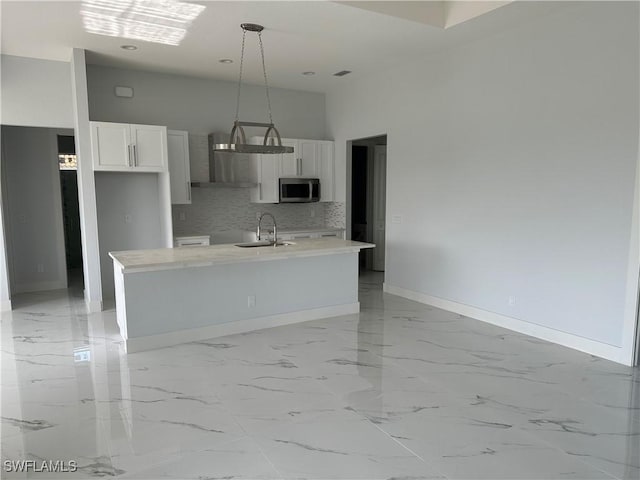 kitchen with white cabinets, sink, hanging light fixtures, and an island with sink