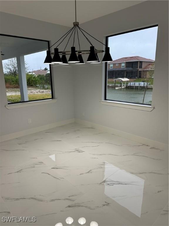 unfurnished dining area featuring a water view and an inviting chandelier