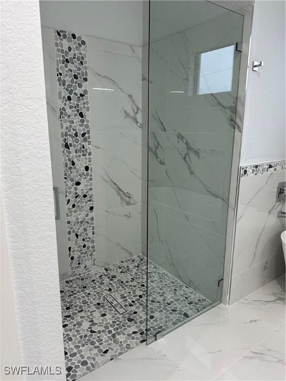 bathroom with tiled shower and tile walls