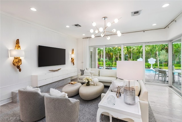 living room with ornamental molding, a chandelier, and hardwood / wood-style flooring