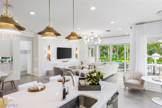 kitchen with sink, dishwasher, light hardwood / wood-style flooring, a chandelier, and decorative light fixtures