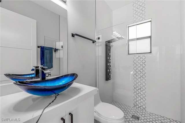 bathroom with a tile shower, vanity, and toilet