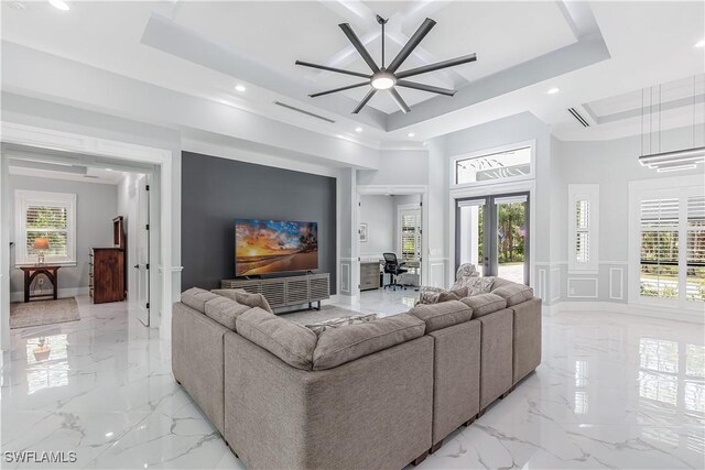 living room with ceiling fan, a raised ceiling, ornamental molding, and french doors