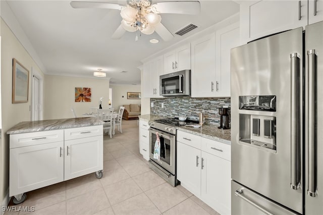 kitchen featuring appliances with stainless steel finishes, tasteful backsplash, light stone counters, light tile patterned floors, and white cabinets