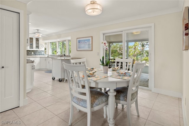 tiled dining area featuring ceiling fan, ornamental molding, and sink